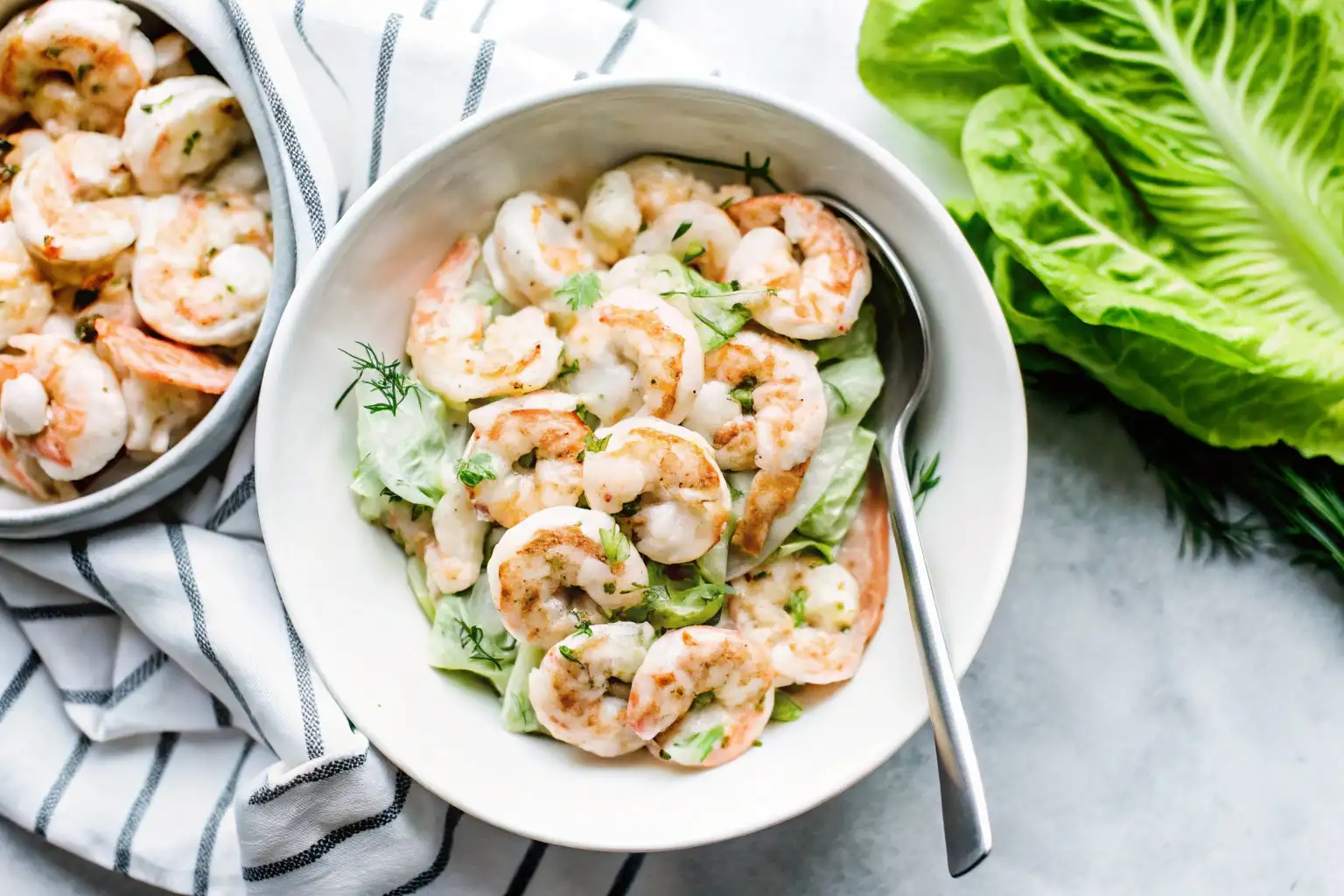 Shrimp salad recipe with creamy dressing, fresh herbs, and crunchy vegetables in a white bowl.